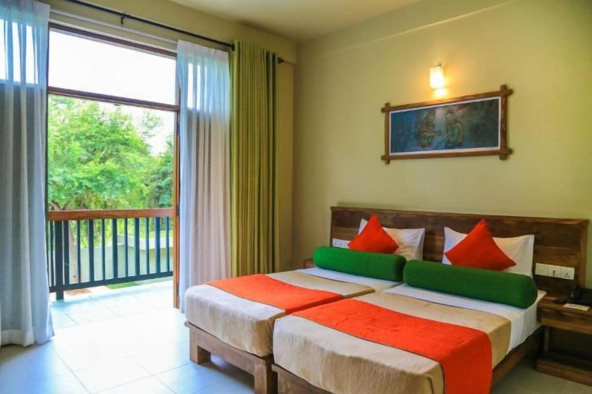 Habitación de hotel con dos camas, un balcón y un cuadro en la pared.