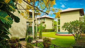 A courtyard with a paved walkway, surrounded by lush greenery and a small pool. - Fresco Water Villa (Sigiriya)
