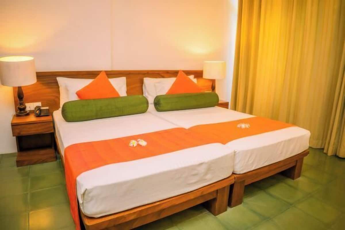 A double bed with two pillows, a nightstand with a lamp, and a wooden headboard.