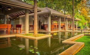 A tranquil outdoor seating area with wooden benches and a central water feature. - Fresco Water Villa (Sigiriya)