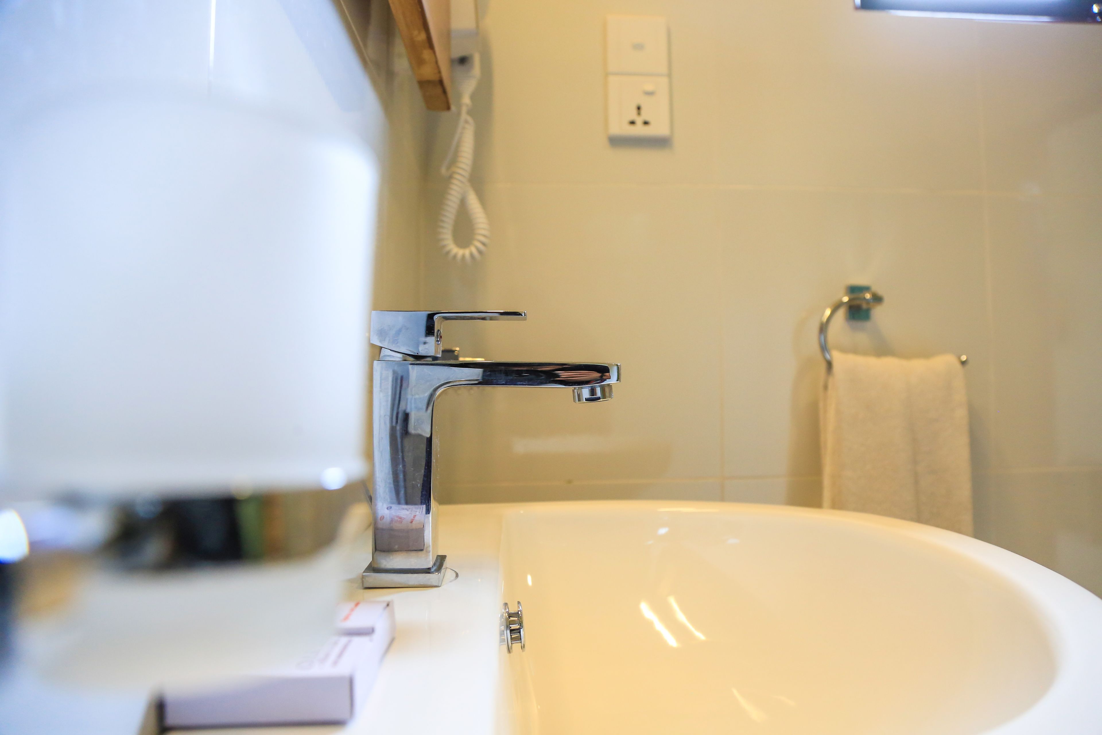 A bathroom with a white sink, chrome faucet, and a towel hanging on a rack.