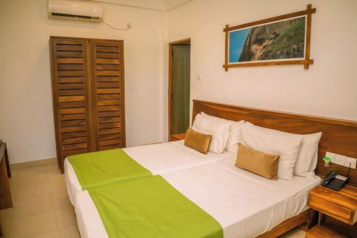 Habitación de hotel con cama, armario de madera, un cuadro en la pared y un teléfono en la mesita de noche.
