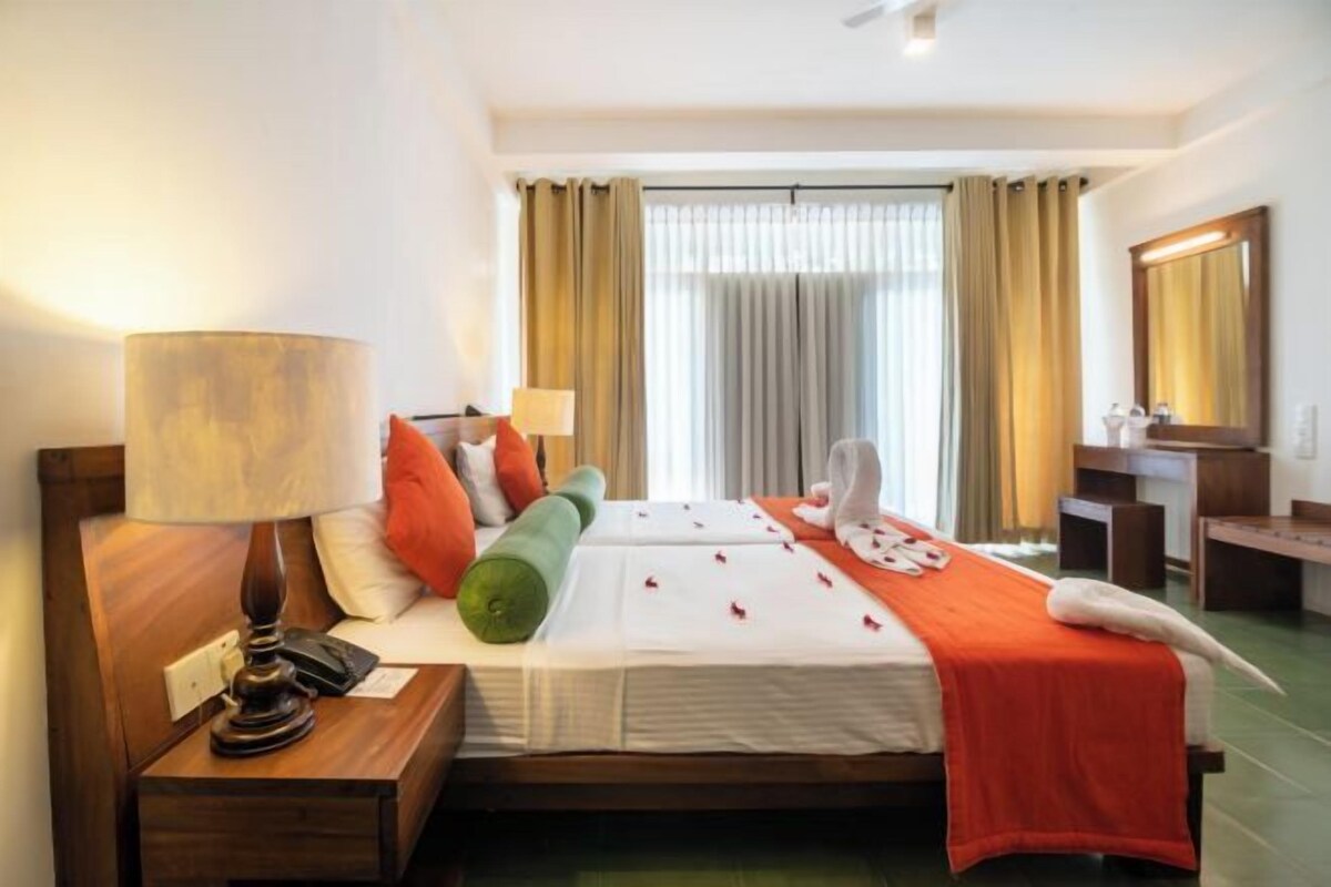 Una habitación de hotel con una cama, lámparas de noche, un escritorio y un espejo.