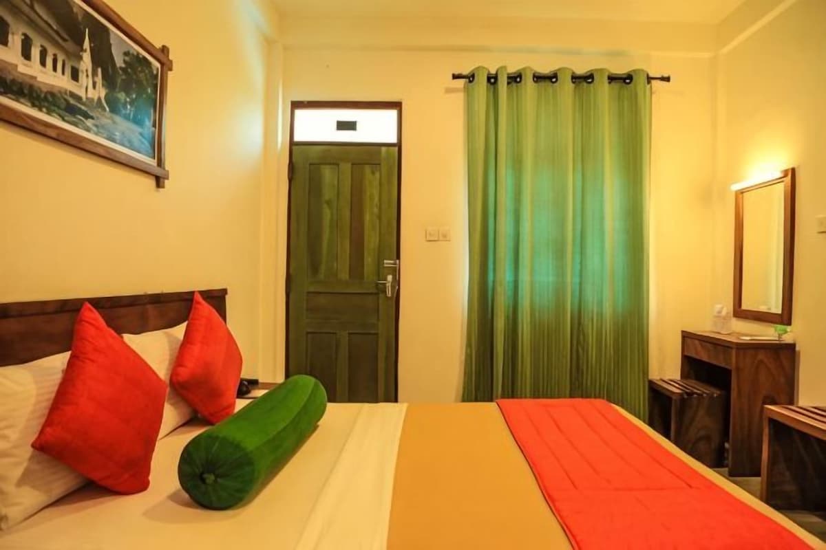Una habitación de hotel con una cama, una puerta, una cortina verde y un espejo.