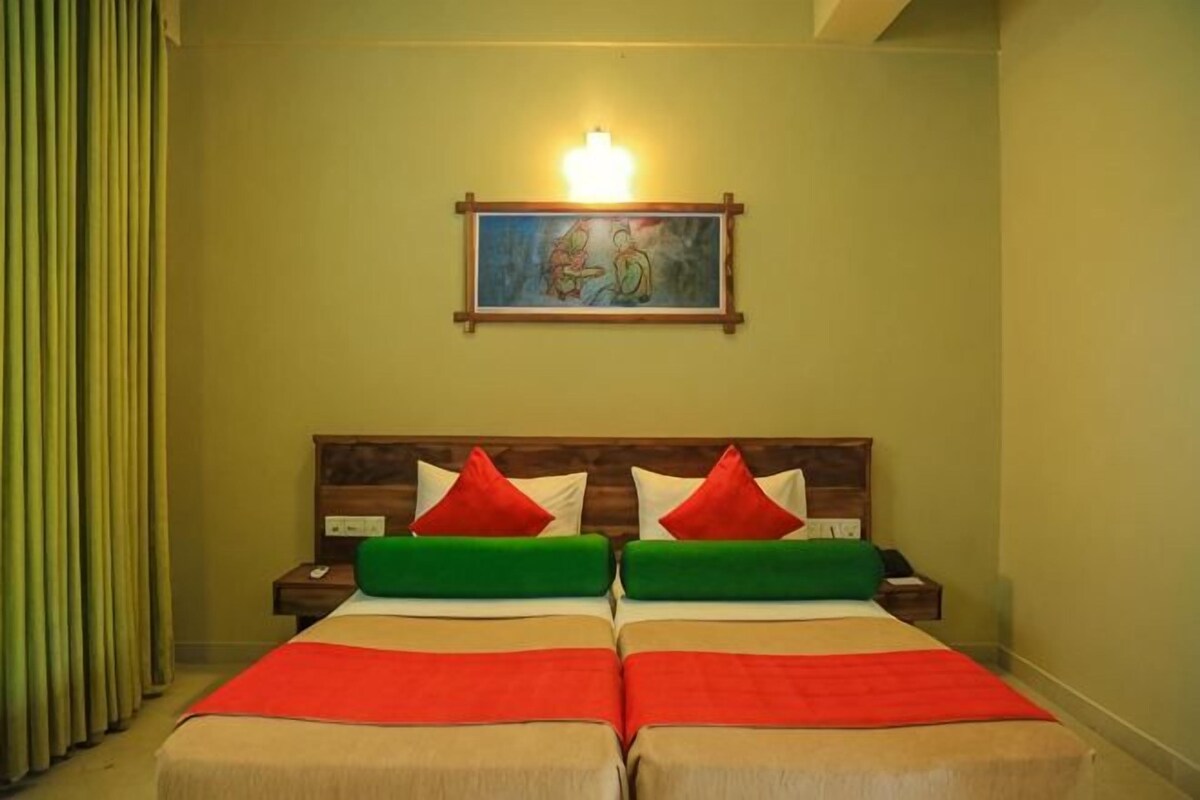 Una habitación con cama doble, dos mesitas de noche, un cuadro en la pared y una ventana con cortinas.