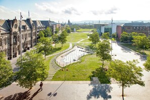 Un edificio histórico con un patio central, una fuente y una estructura de vidrio moderna al fondo.