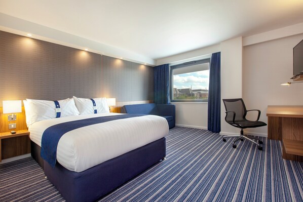 A hotel room with a large bed, a desk, a chair, a window with curtains, and a view of buildings outside. - Holiday Inn Express Middlesbrough - Centre Square by IHG (Middlesbrough)