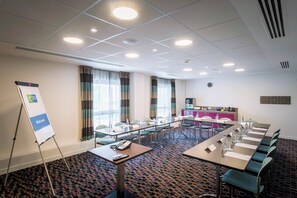 A conference room with a long table, chairs, a whiteboard, and a clock on the wall.