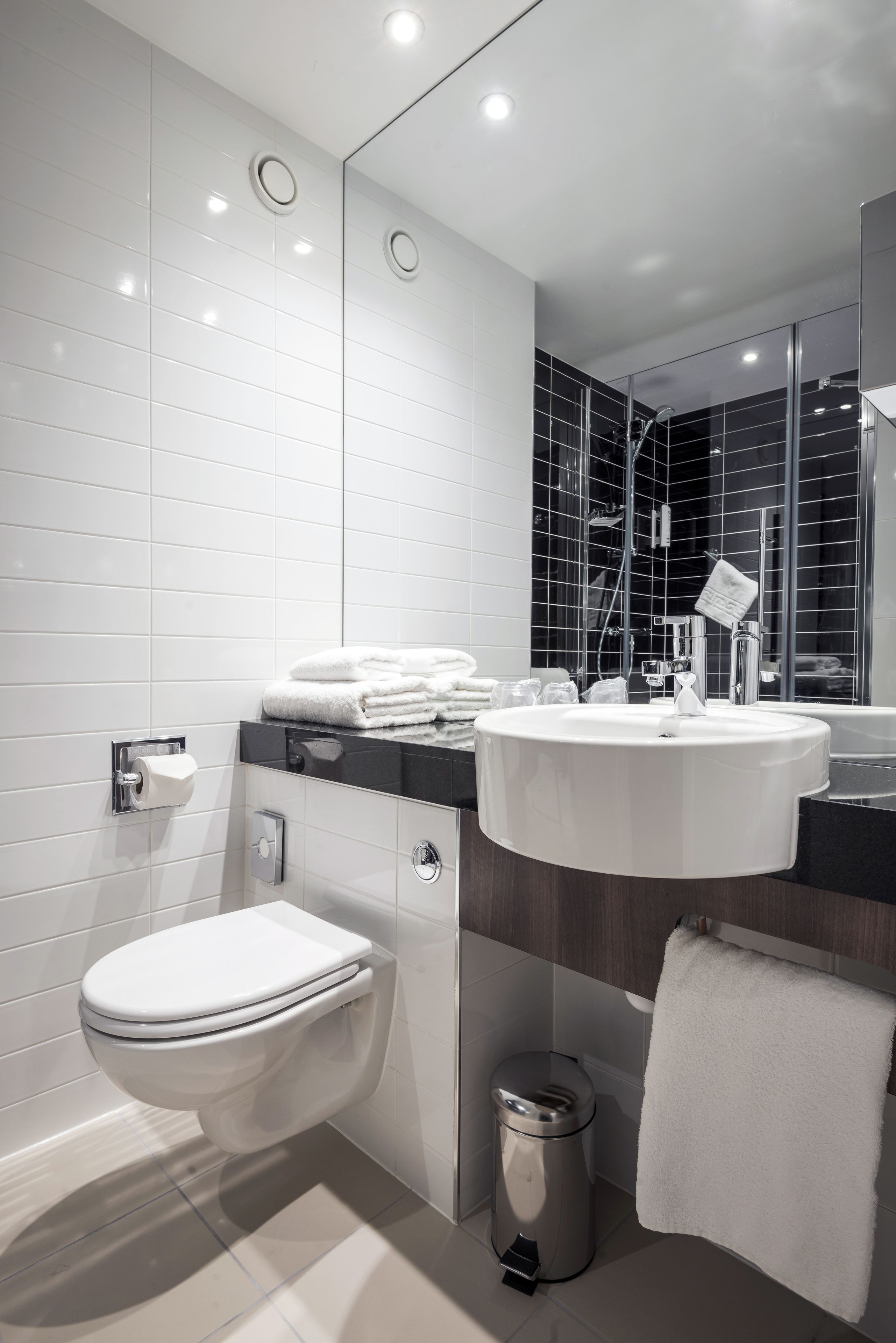 A modern bathroom with a toilet, sink, and mirror.
