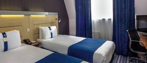 A hotel room with two beds, a desk, a chair, and a television.