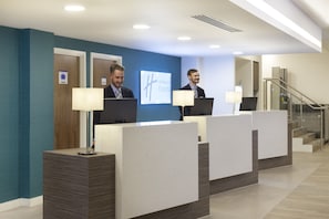 A hotel reception area with a blue wall, a Holiday Inn Express sign, and a staircase to the right. - Holiday Inn Express Middlesbrough - Centre Square by IHG (Middlesbrough)