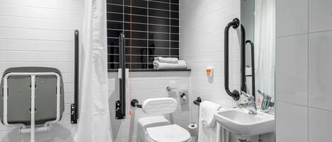 Un baño moderno con inodoro, lavamanos y barras de apoyo.
