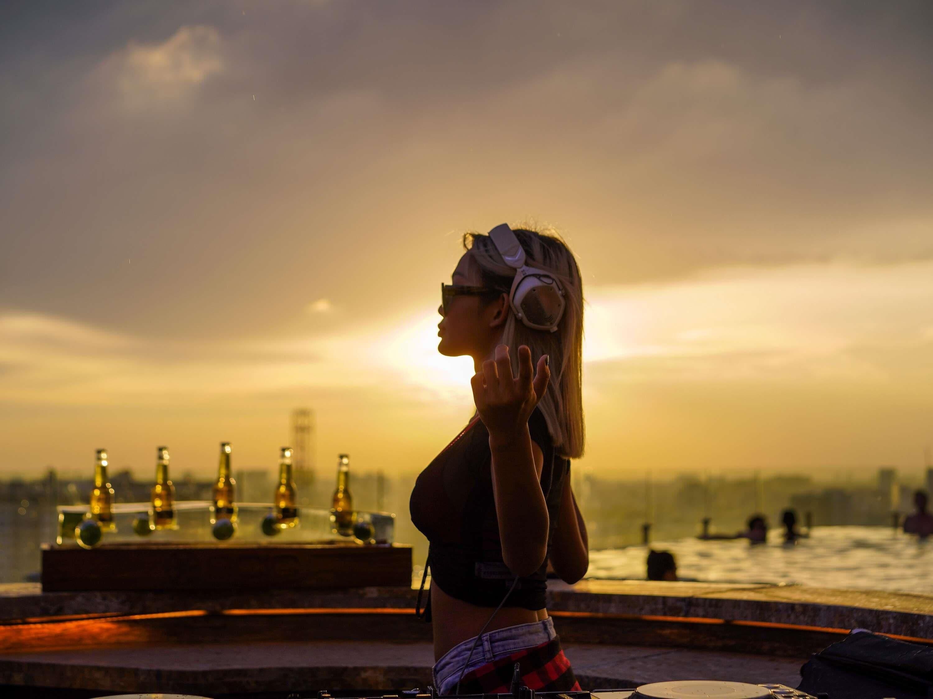 Una persona in piedi su un tetto con un tramonto sullo sfondo, che domina un panorama urbano.