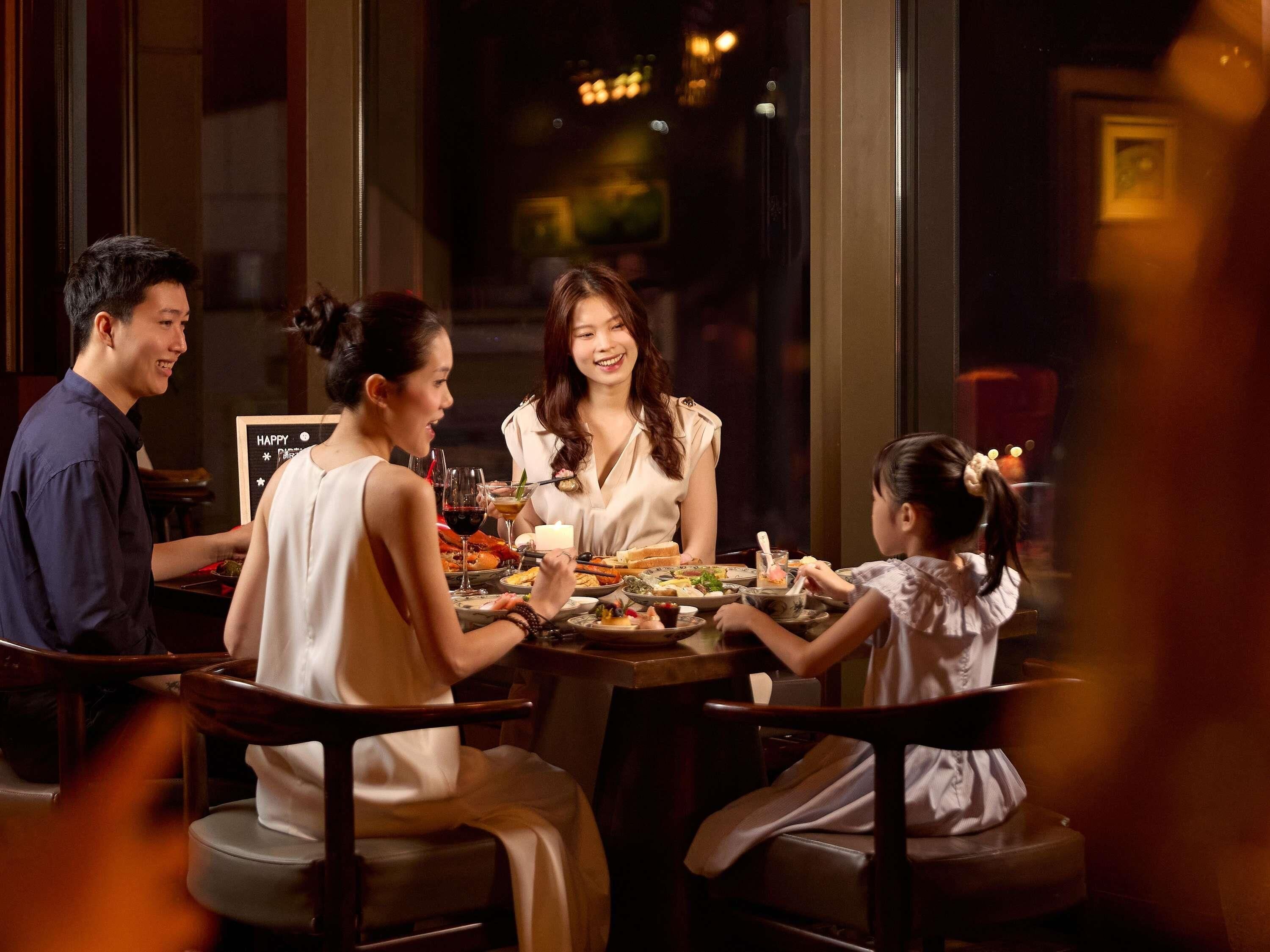 A group of people dining at a restaurant with a table set for multiple courses.
