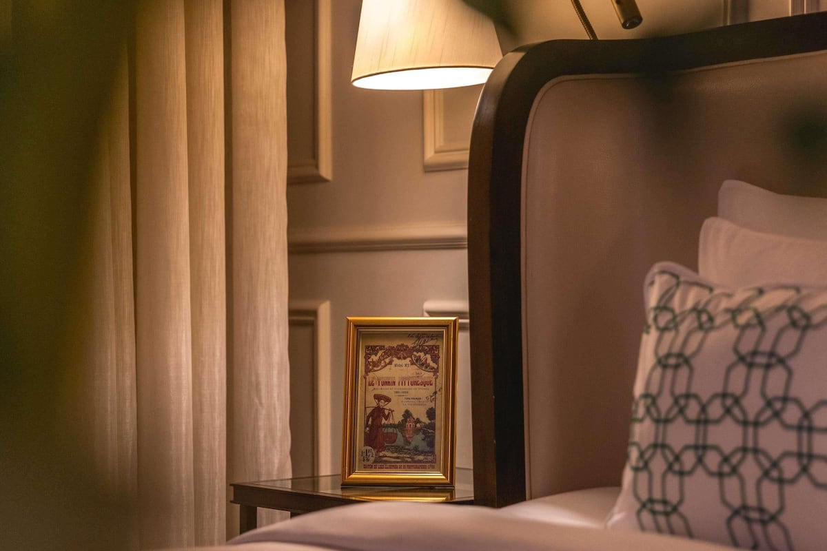Una habitación de hotel con una cama, un cuadro en la mesita de noche y una lámpara.