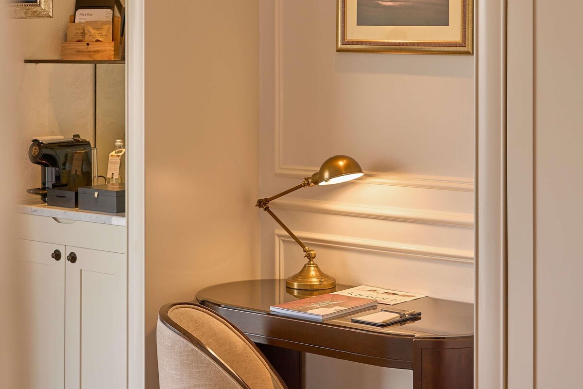 Un bureau avec une lampe, une chaise et un organiseur de bureau contenant un livre et un bloc-notes.