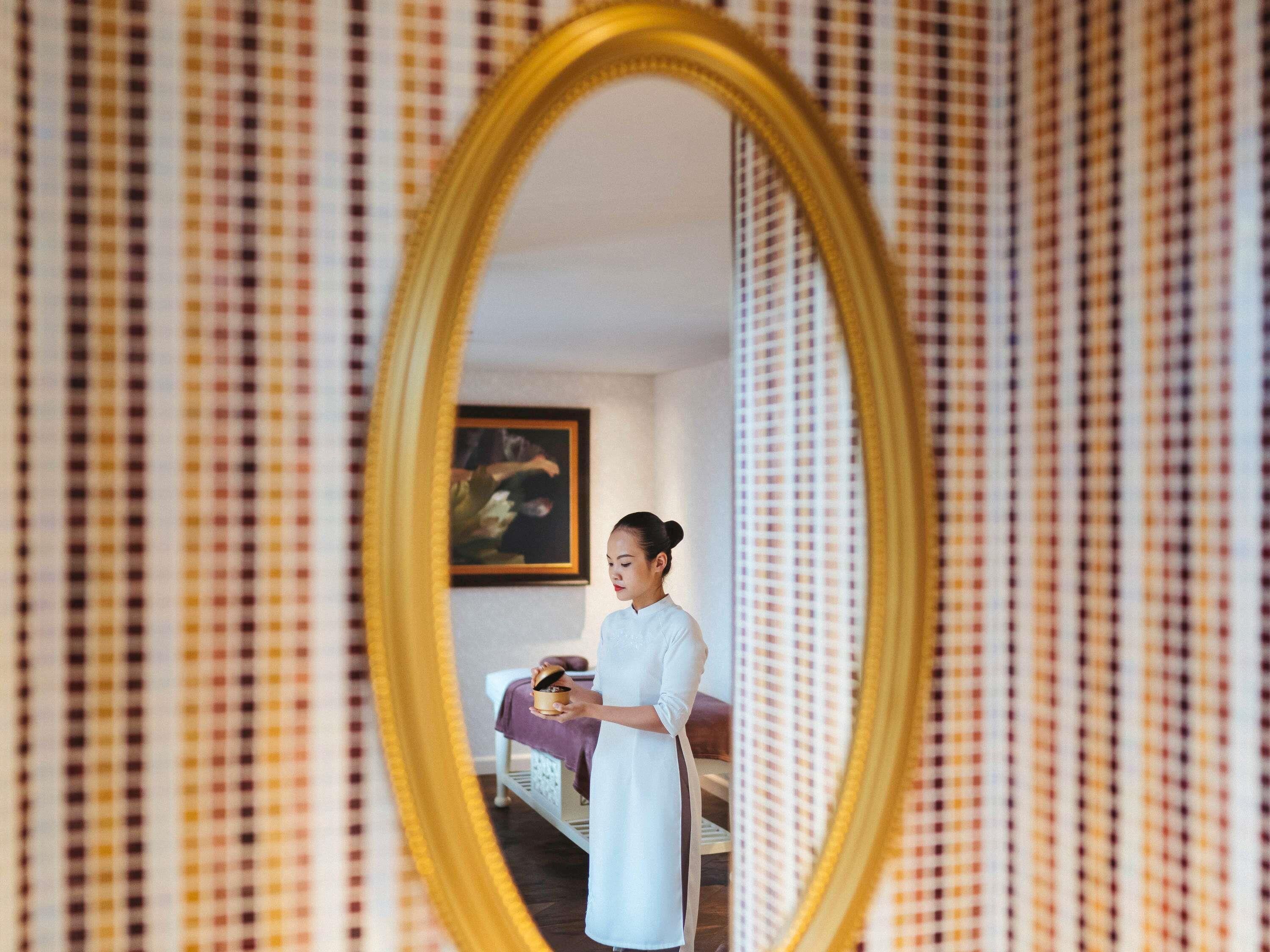 A room with a checkered wallpaper, a bed with a purple blanket, and a painting on the wall.