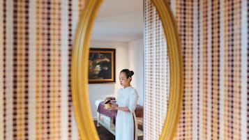 A room with a checkered wallpaper, a bed with a purple blanket, and a painting on the wall.