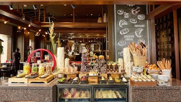 Una vitrina de pastelería con diversos productos de repostería, un menú en una pizarra y un adorno circular rojo.