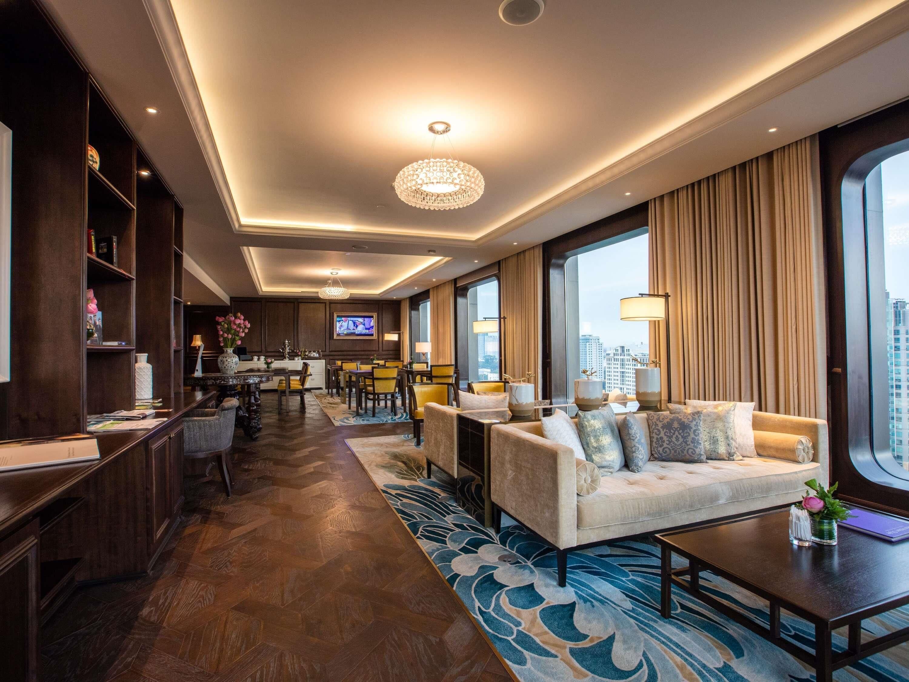 A hotel lobby with a dining area, a sofa set, and a TV screen.
