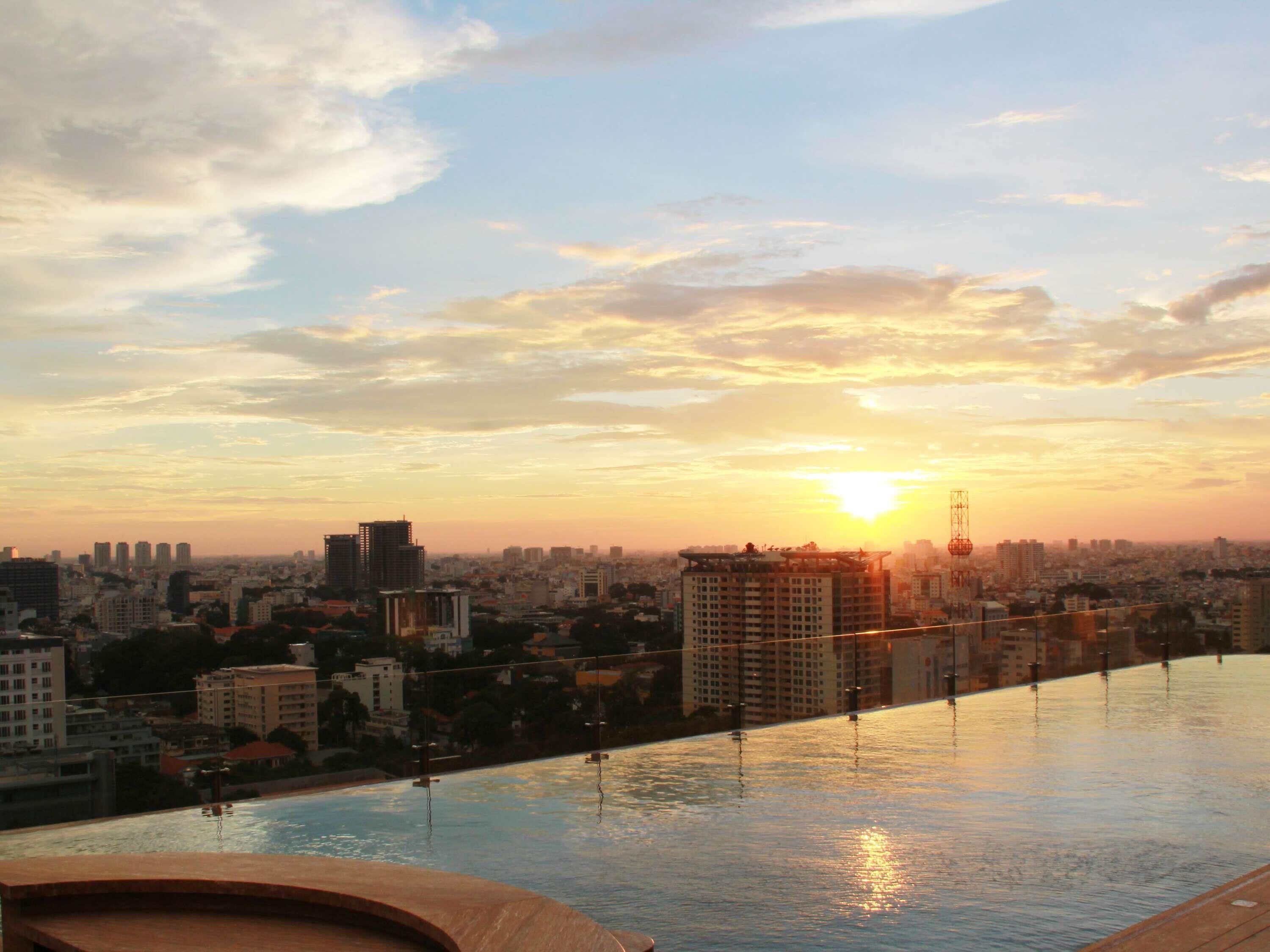 A rooftop pool with a cityscape view at sunset.