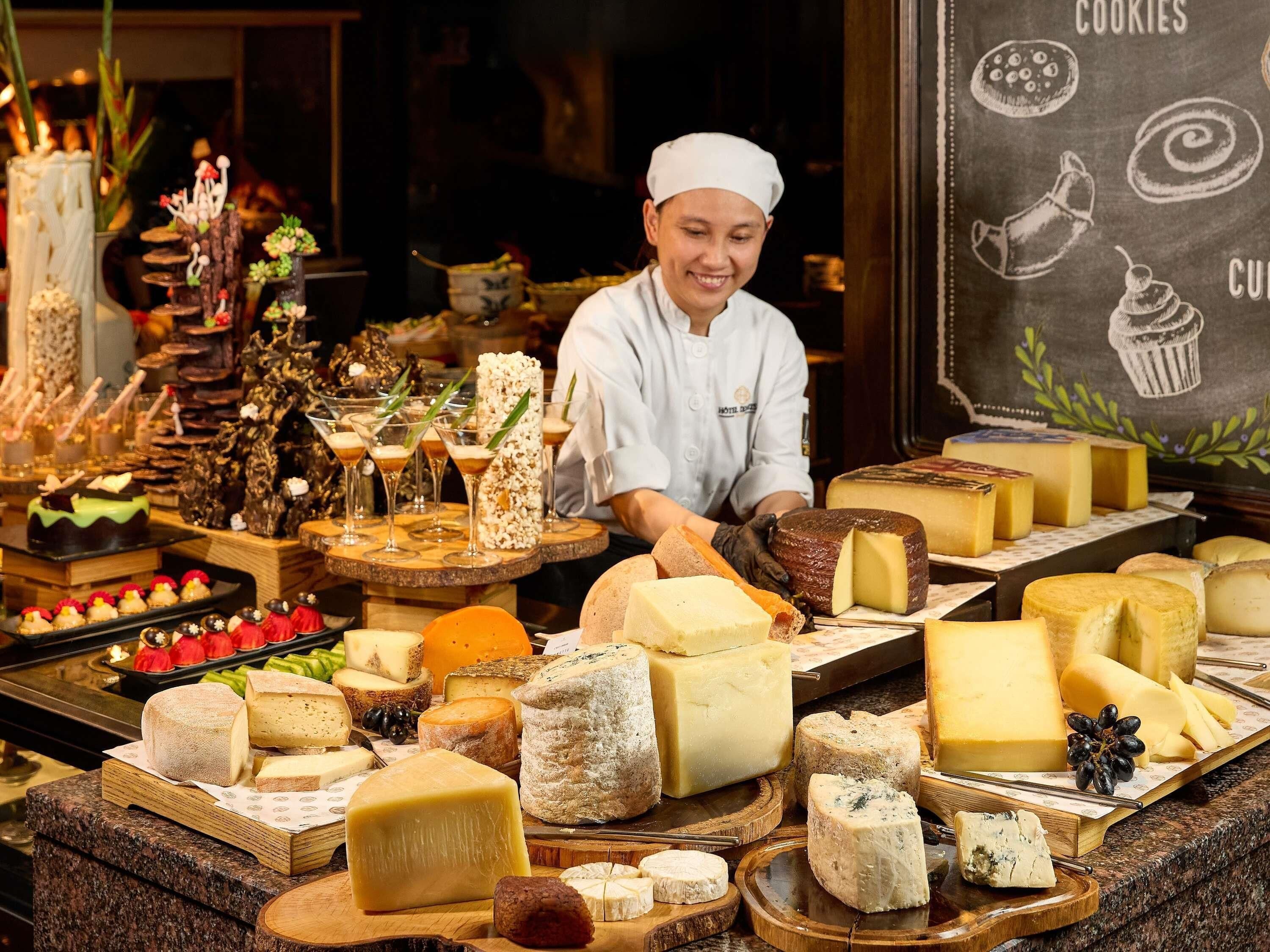 A cheese display with various types of cheese and a chalkboard menu in the background.