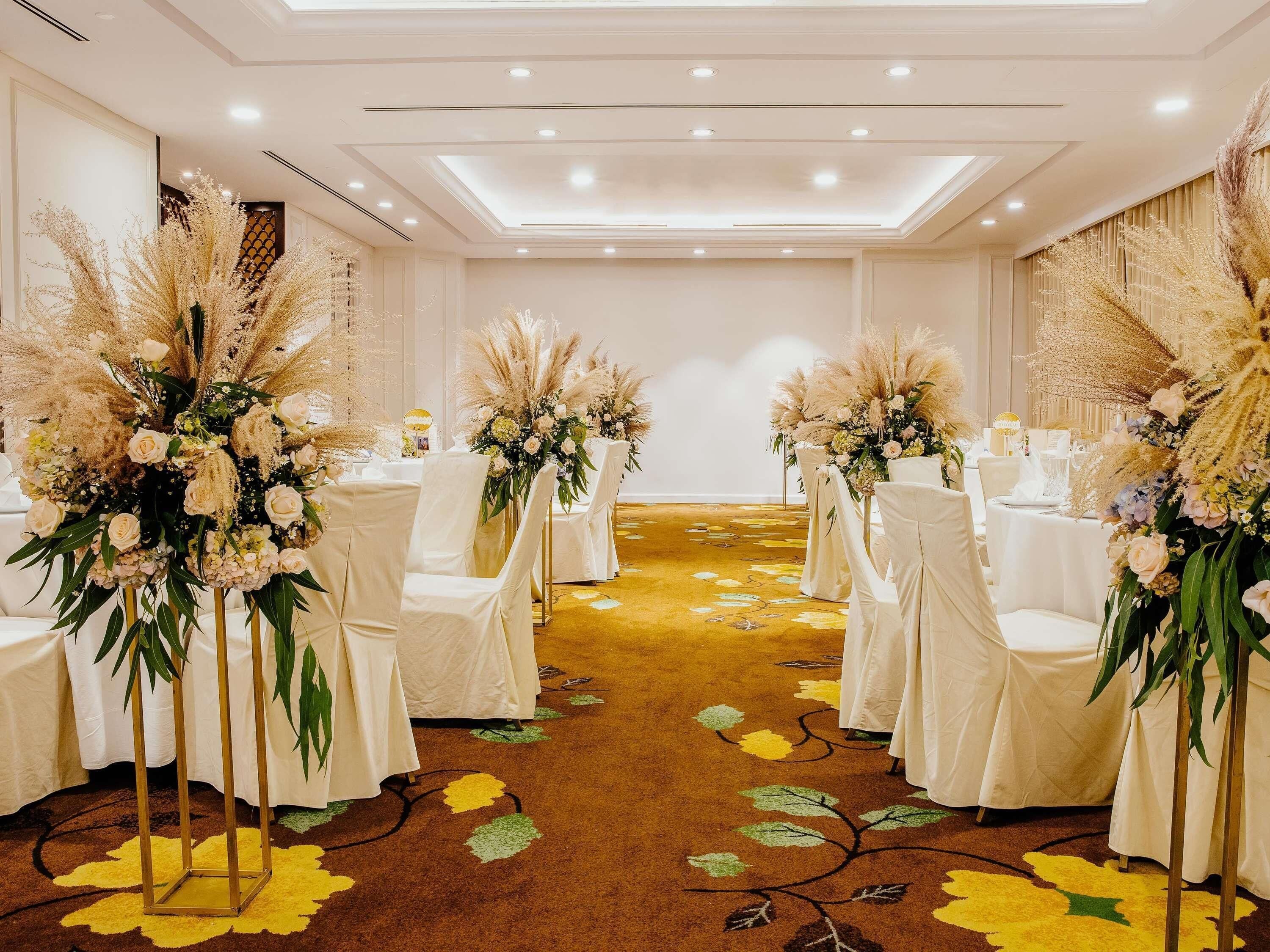A conference room with white chairs, round tables, and floral centerpieces.