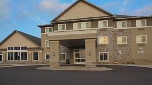 A two-story building with a covered entrance and a stone facade. - Gateway Park Hotel and Suites (Tea)