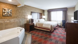 A hotel room with a large bed, a separate bathroom with a bathtub, and a desk with a television. - Gateway Park Hotel and Suites (Tea)