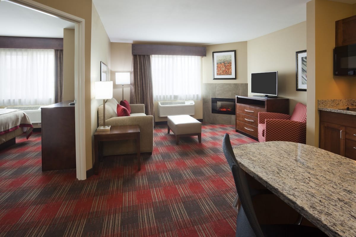 Ein Hotelzimmer mit Bett, Schreibtisch, Stuhl, Fernseher und Mikrowelle.