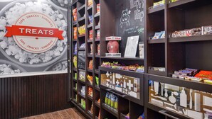 A snack display area with various packaged snacks and a sign reading "THE HAPPY HIP". - Hampton Inn & Suites Hutto Austin (Hutto)