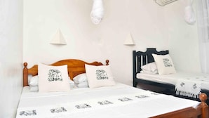 A bedroom with two beds, each with a canopy and matching pillows.