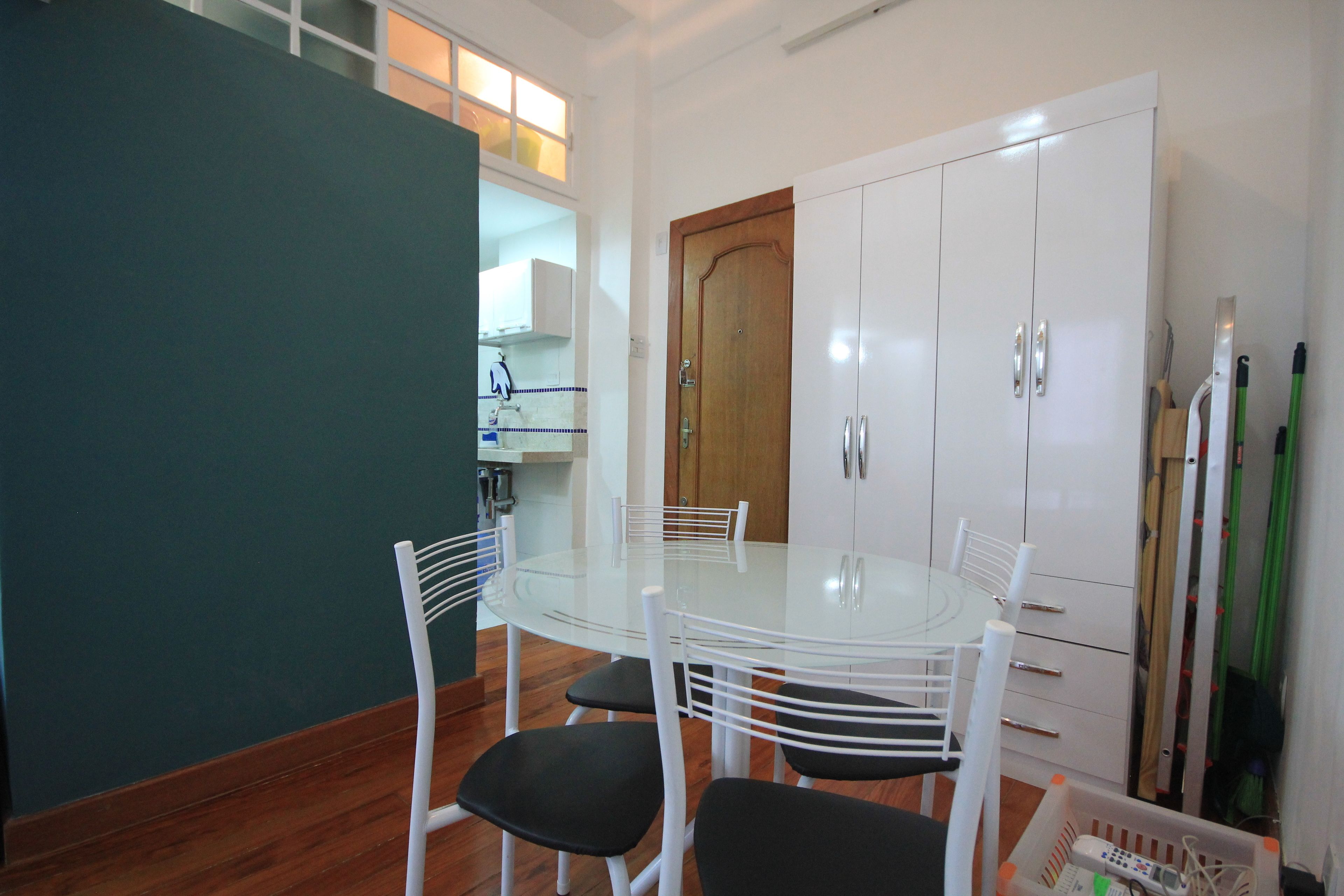 Un coin repas avec une table en verre et des chaises blanches, un meuble blanc et une porte en bois.