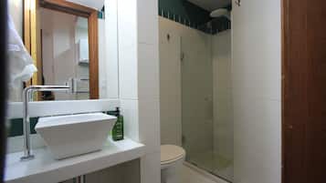 A bathroom with a white sink, a toilet, and a glass shower enclosure.