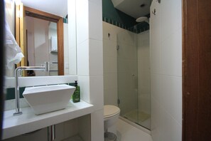 Une salle de bain avec un lavabo blanc, des toilettes et une douche à parois de verre.