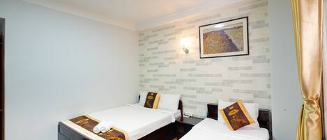 A hotel room with two single beds, a nightstand, a wall-mounted light, and a painting.