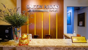 La zona de recepción del Hotel Saigon Amigo, con una pared de madera, un mostrador de recepción y un cartel que indica la recepción.