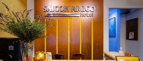 L'espace d'accueil de l'hôtel Saigon Amigo est doté d'un mur en bois, d'un comptoir de réception et d'une enseigne indiquant la réception.