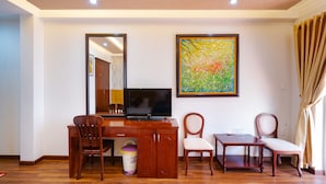 Una habitación con un escritorio de madera, un televisor y dos sillas.