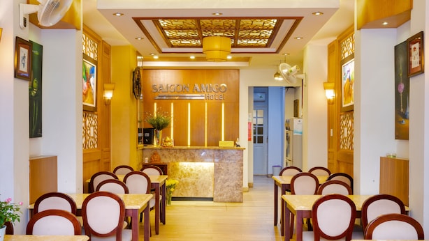 Zona de recepción de un hotel con mostrador de mármol, sillas de madera y ventilador de techo.