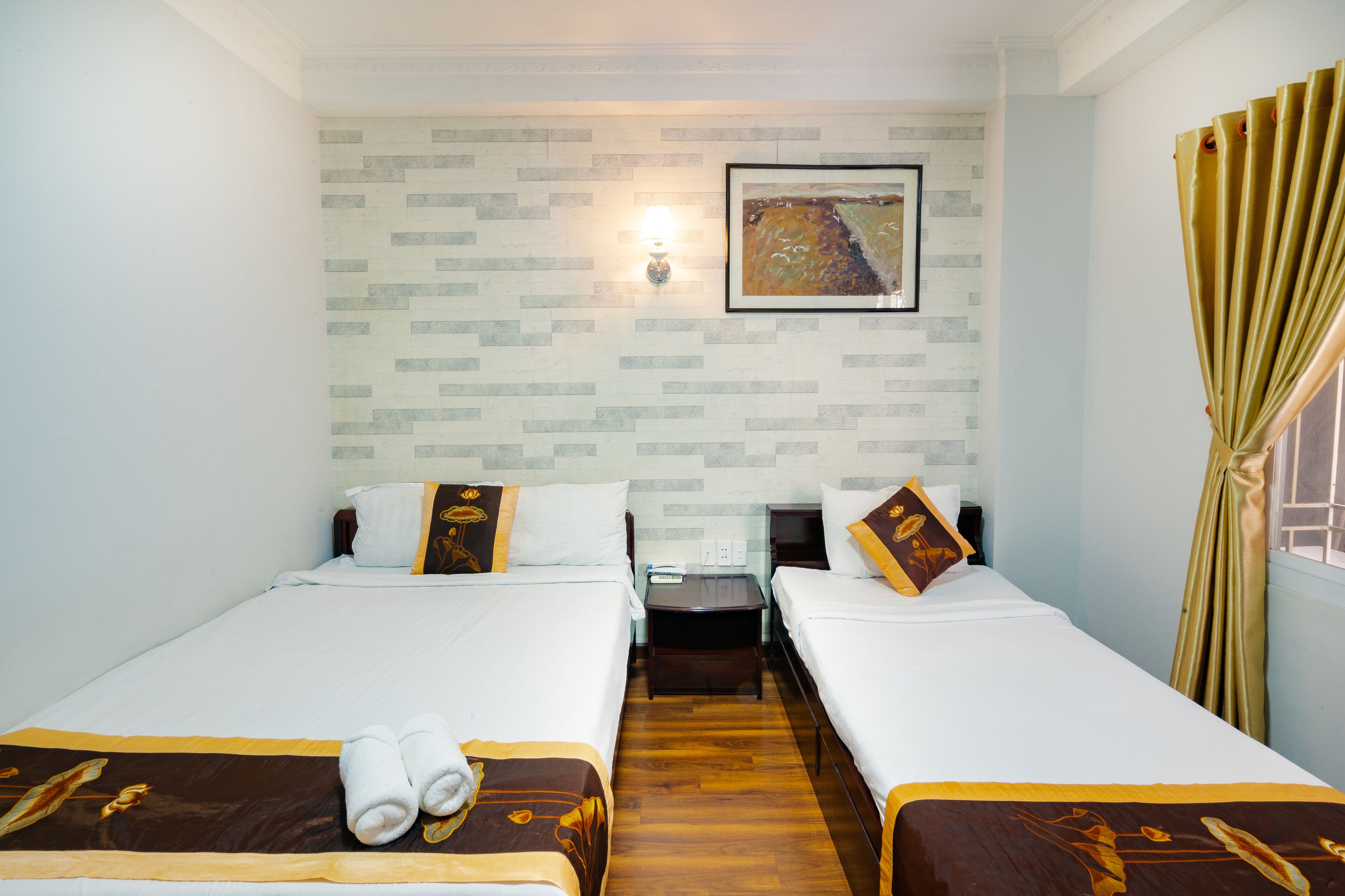 A hotel room with two beds, a nightstand, a lamp, and a painting on the wall.