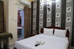 Ein Hotelzimmer mit einem Bett, einem Nachttisch, einem kleinen Tisch mit einer Dekoration und einer Wand mit einem Muster.