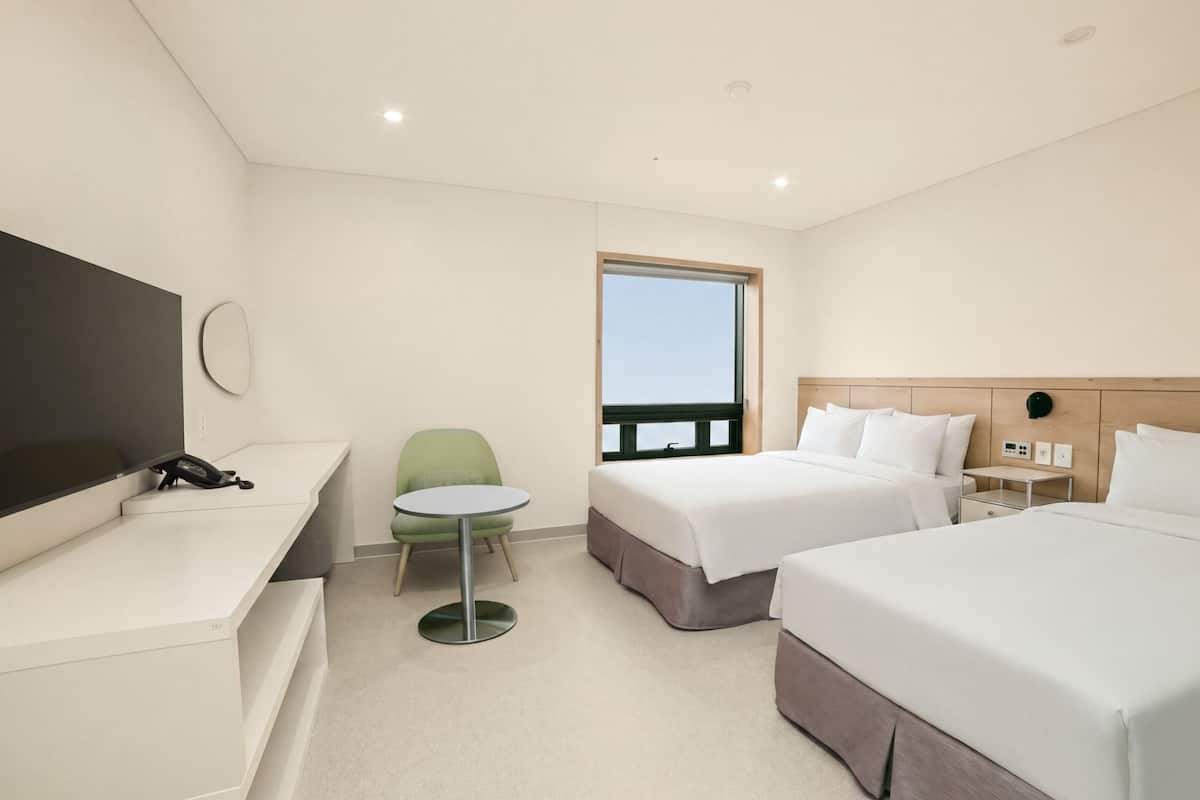 Una habitación de hotel con cama, mesita de noche, silla y televisión.