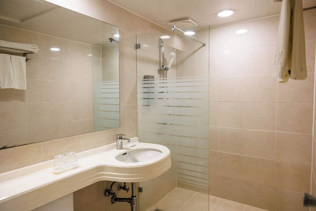 A modern bathroom with a large mirror, a sink, and a shower.