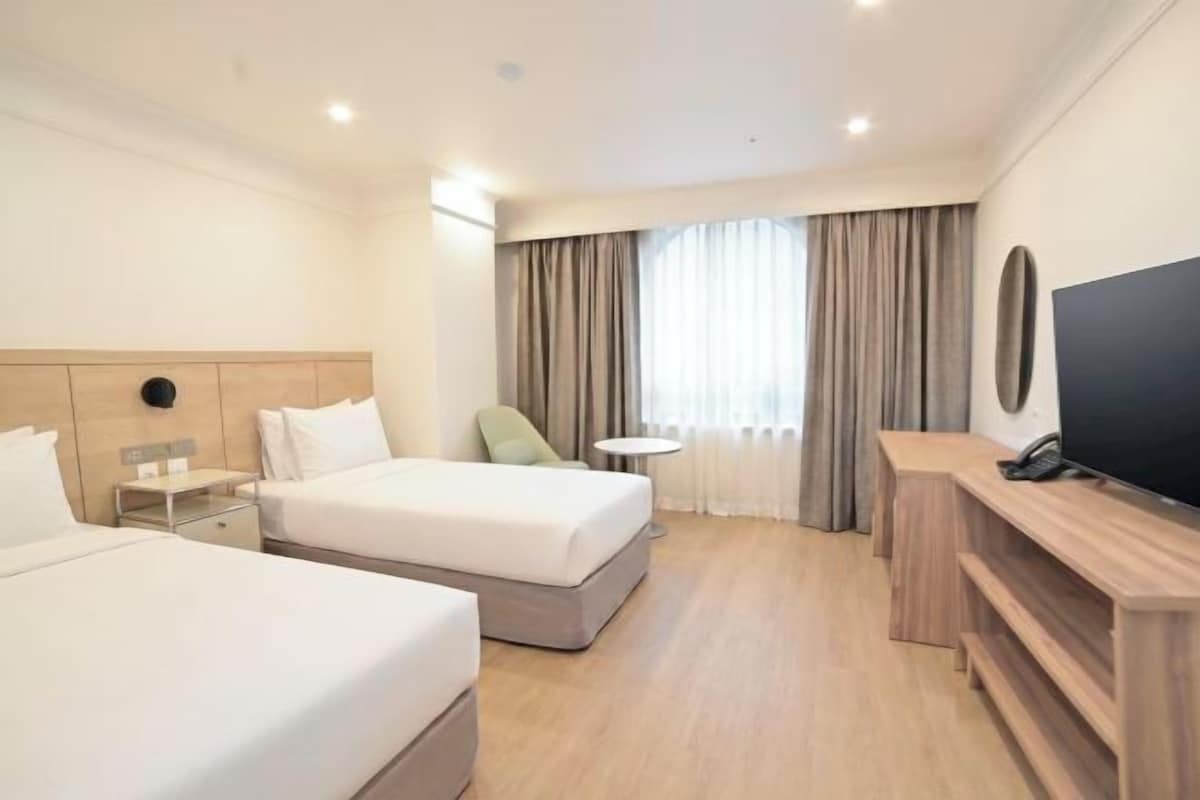 A hotel room with two beds, a TV, a small table, and a desk.