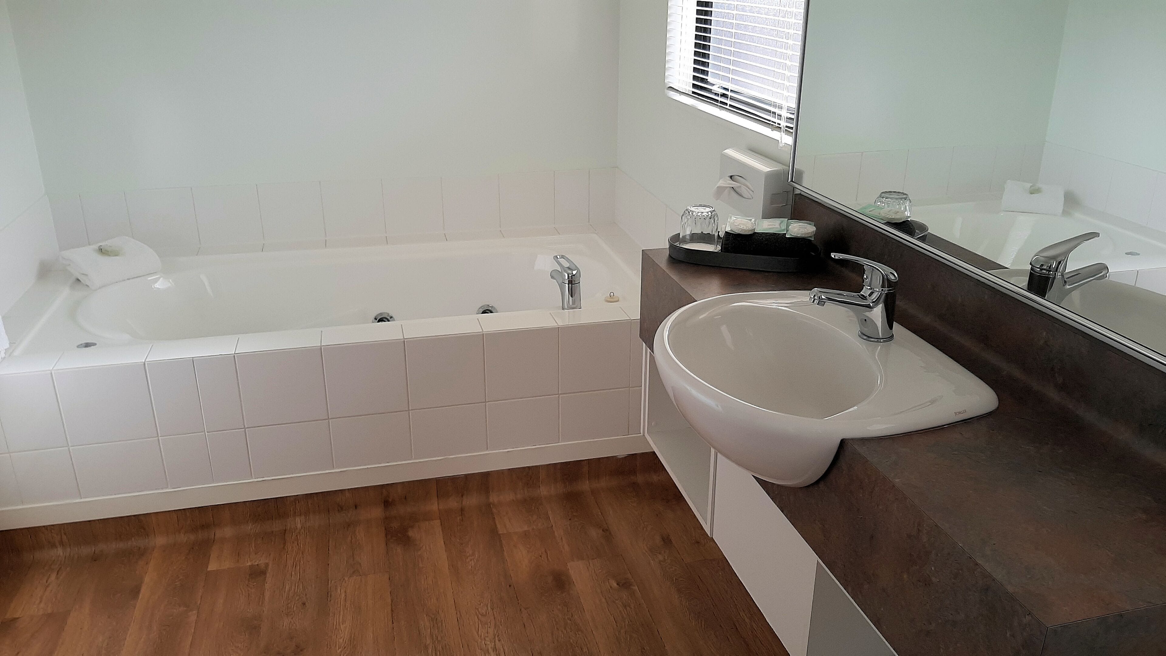 Une salle de bain moderne avec une baignoire, un lavabo et un miroir.