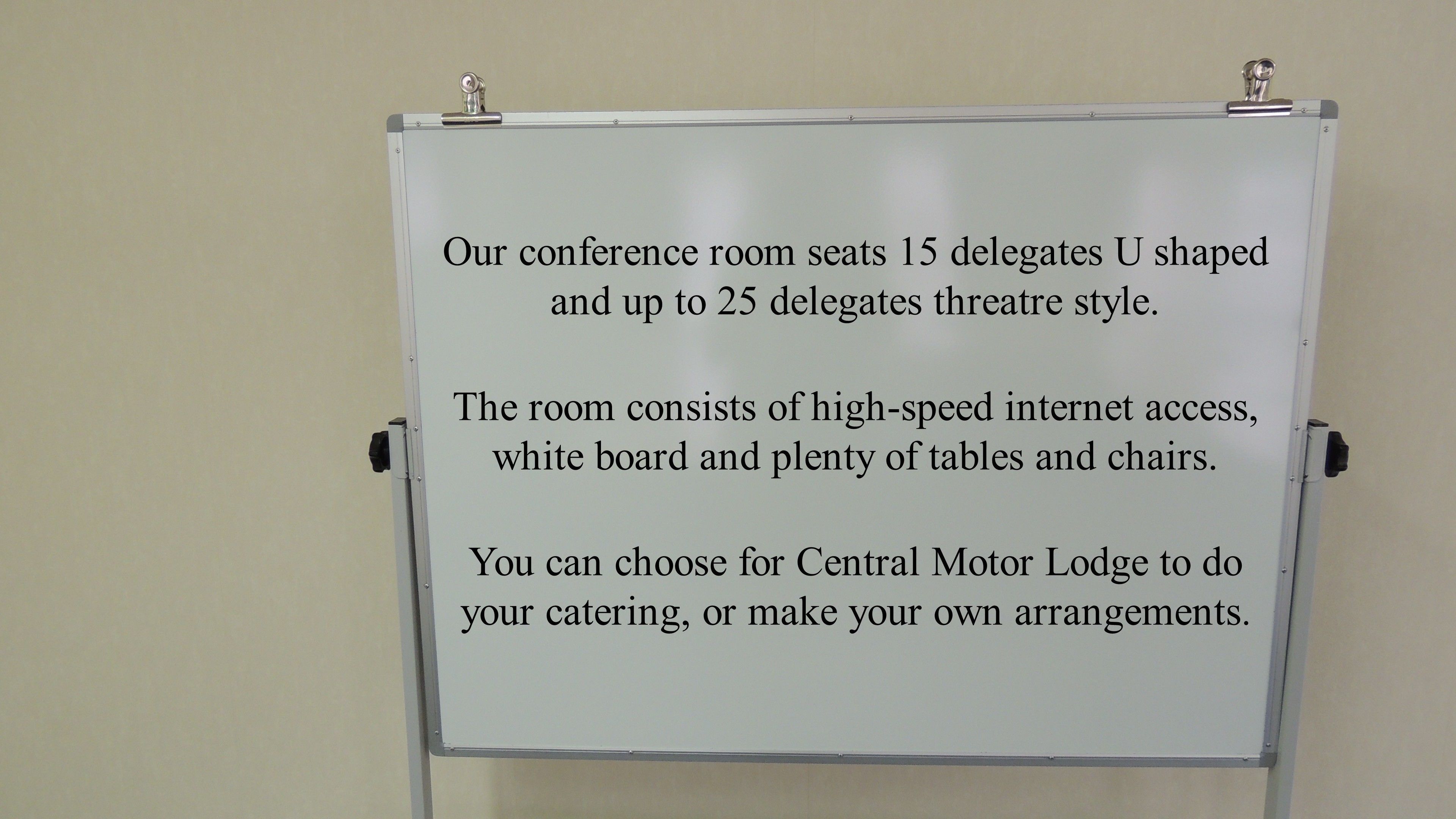 Una pizarra con texto que describe la capacidad de asientos de una sala de conferencias, acceso a internet y opciones de catering.