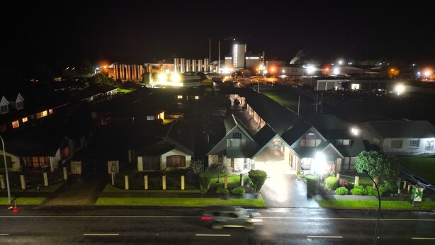 A nighttime view of a residential area with houses and a large industrial facility in the background. - Central Motor Lodge (Morrinsville)