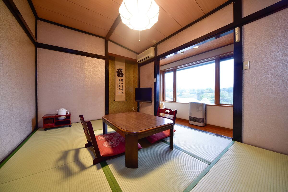 Una habitación japonesa tradicional con suelo de tatami, una mesa de madera y sillas.
