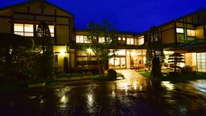 Ein traditionelles japanisches Gebäude mit überdachter Eingangspartei und einem feuchten Innenhof bei Nacht.